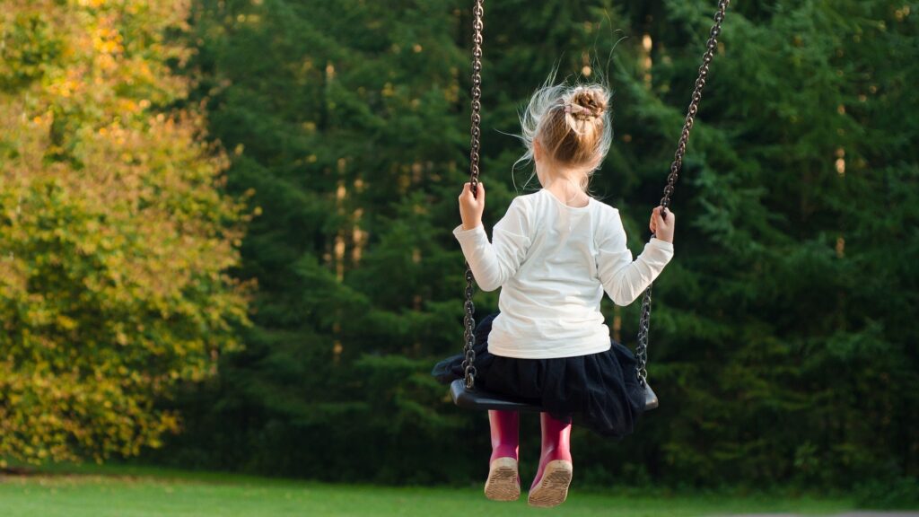 A young girl on a swing in a park.